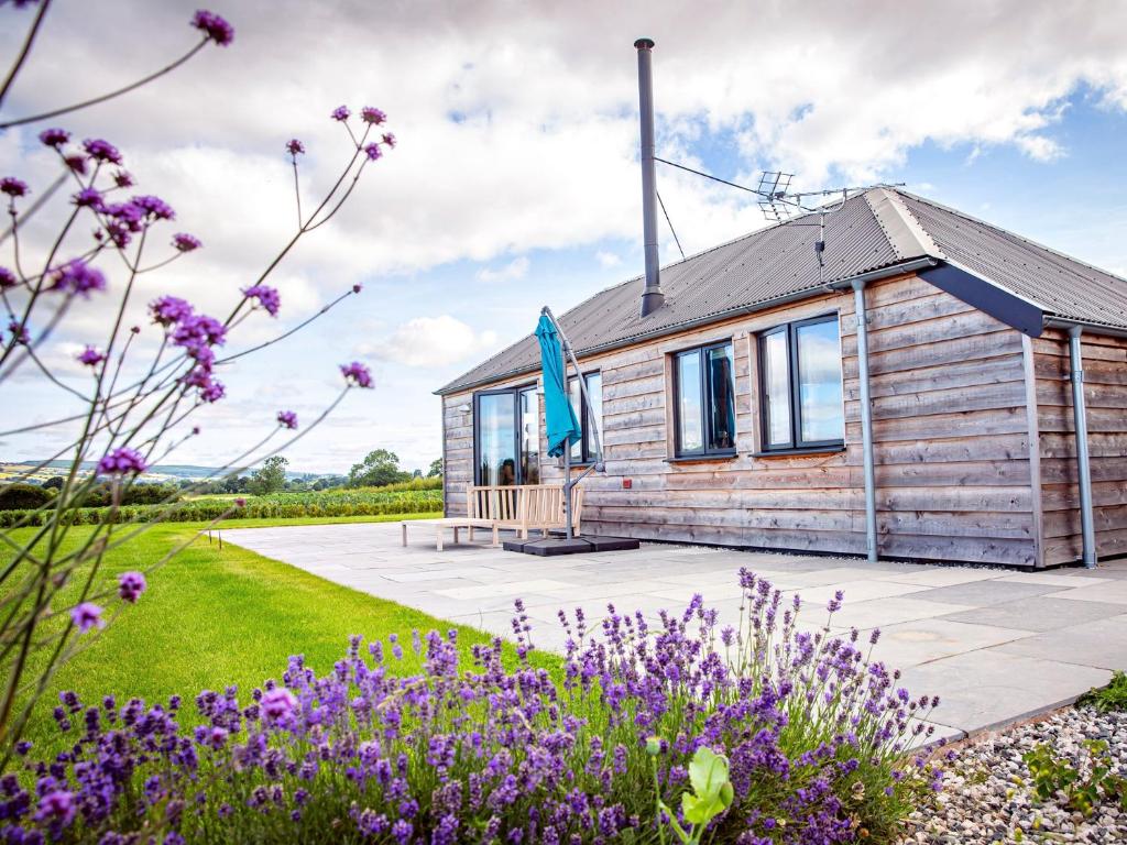 a wooden cabin in a garden with purple flowers at 2 Bed in Leominster 80510 in Eye