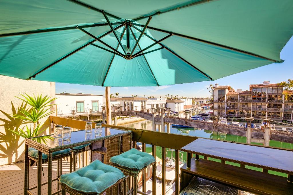 un patio con mesas, sillas y una sombrilla en Waterfront Long Beach Condo with Pool Access!, en Long Beach