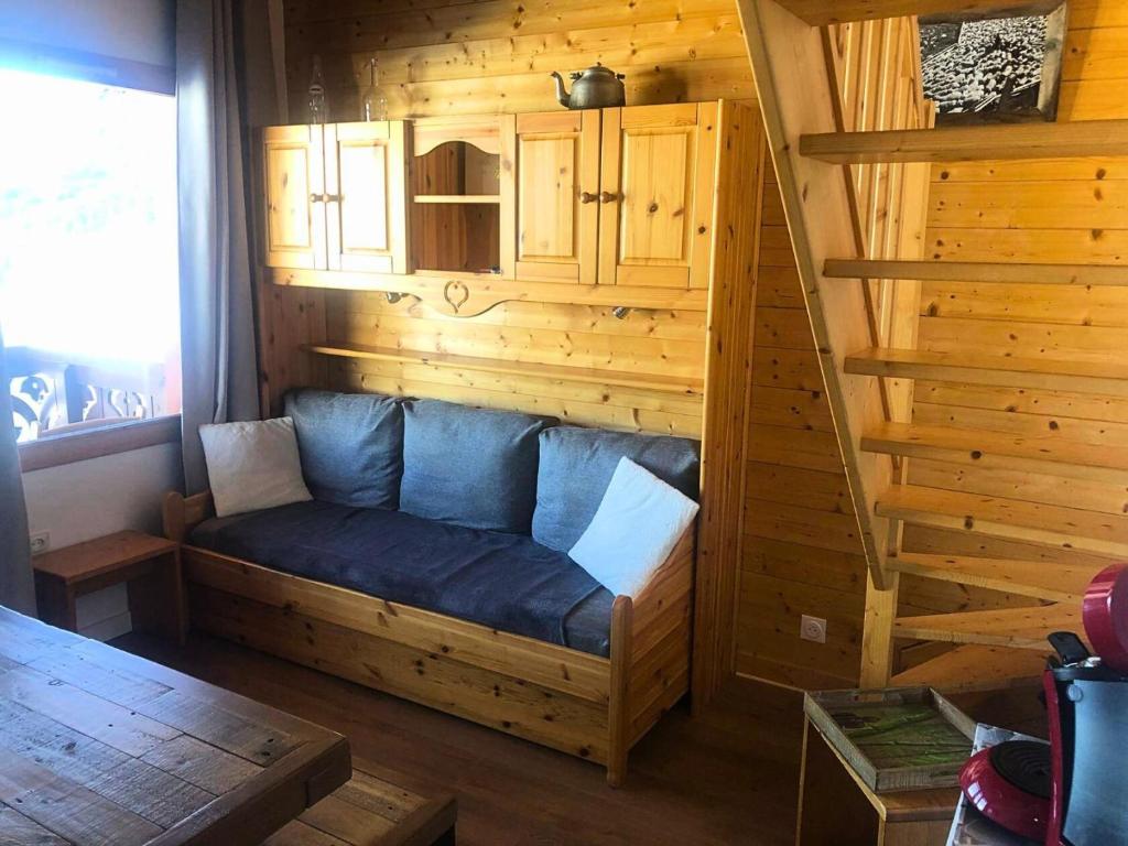 une chambre avec un canapé bleu dans une cabane en rondins dans l'établissement Résidence Camarine - La Camarine 19 - Joli 2 pièces avec mezzanine MAE-4614, à Valmorel