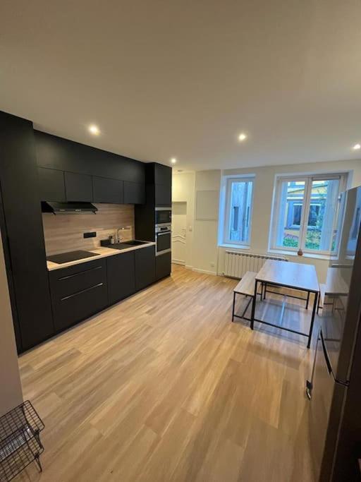 Il comprend une grande cuisine avec du parquet et des armoires noires. dans l'établissement Appartement Saint-Etienne hyper centre, à Saint-Étienne