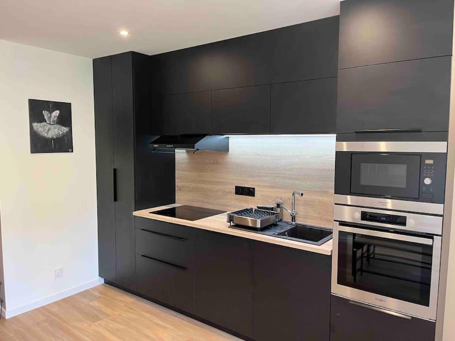 a kitchen with black cabinets and a sink and a microwave at Appartement Saint-Etienne hyper centre in Saint-Étienne