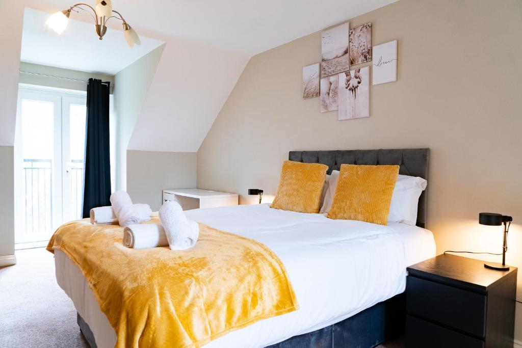 a bedroom with a large bed with yellow pillows at Entire 4 Bed Cosy Luxury Spacious house in Huntingdon