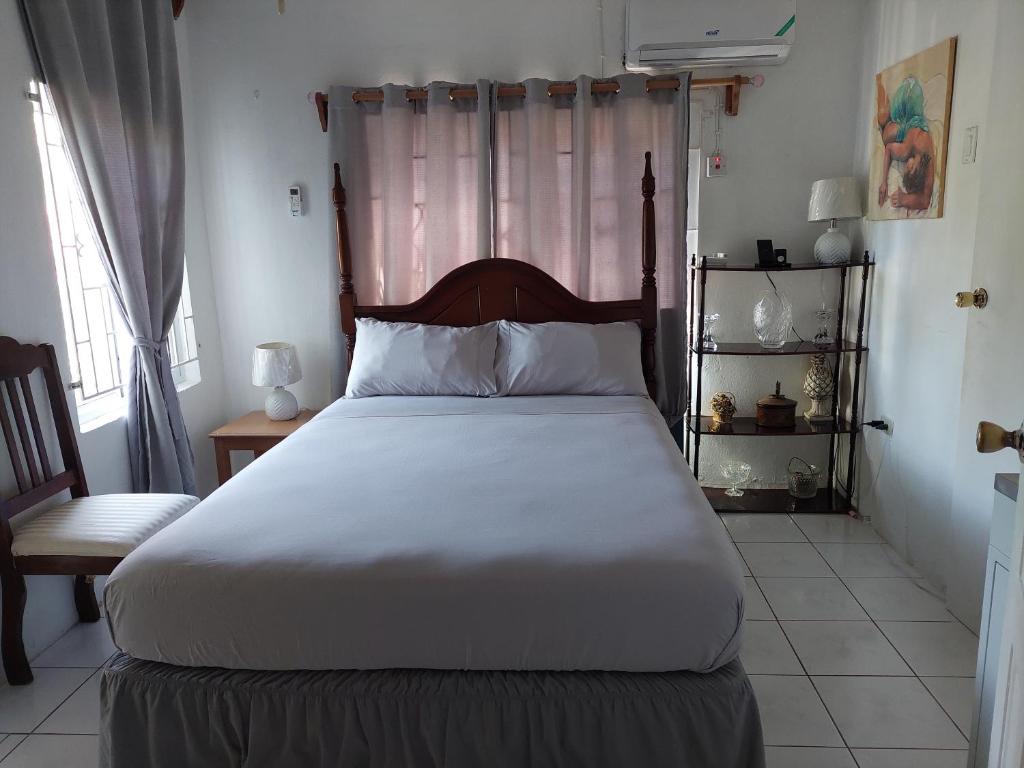 um quarto com uma grande cama branca e uma cadeira em Hunter's Place - Tim Pappies em Port Antonio