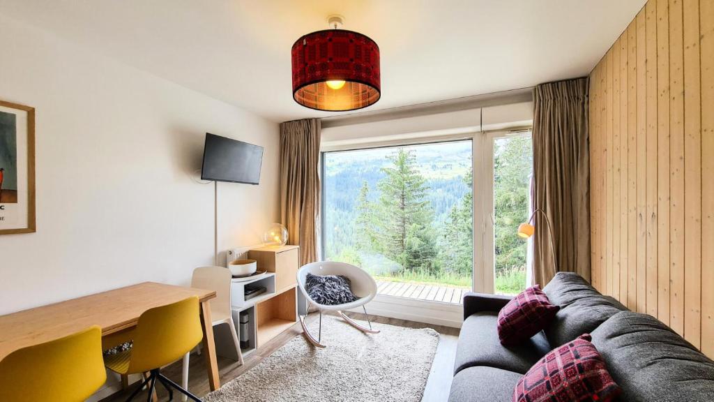 ein Wohnzimmer mit einem Sofa, einem Tisch und einem Fenster in der Unterkunft Résidence Les Pleiades - 2 Pièces pour 6 Personnes 794 in Magland
