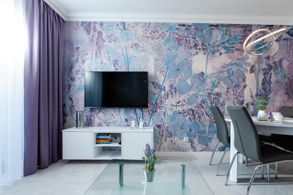 a living room with a tv on a purple wall at Apartament LAWENDOWY Gardenia Dziwnów z widokiem na morze EPapartamenty in Dziwnów