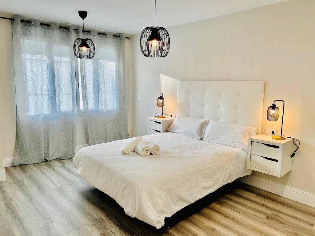 einem weißen Hund, der in einem Schlafzimmer auf einem Bett liegt in der Unterkunft Gran Capitán Home in Córdoba
