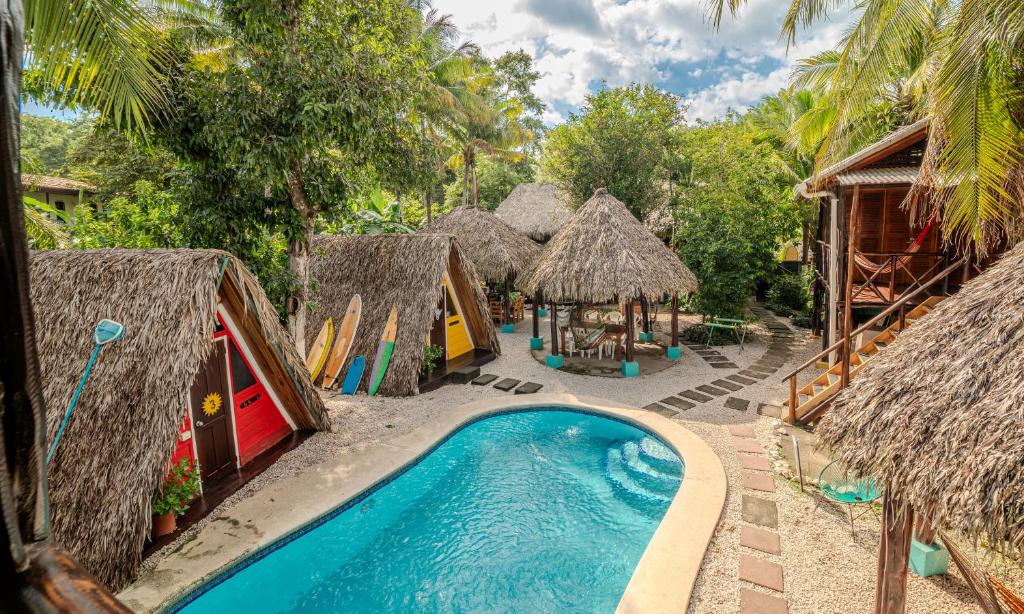 a resort with a swimming pool and some huts at Playa Grande Surf Camp in Playa Grande