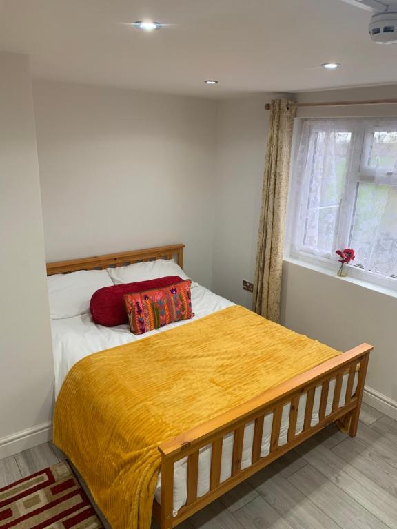ein Schlafzimmer mit einem Bett mit einer gelben Decke darauf in der Unterkunft Goodmayes Park Home in Goodmayes