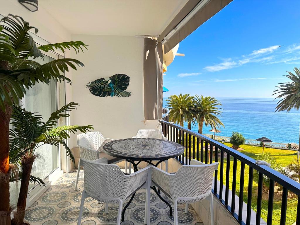 balkon ze stołem i krzesłami oraz oceanem w obiekcie Acapulco Playa 302 Apartments Casasol w mieście Nerja