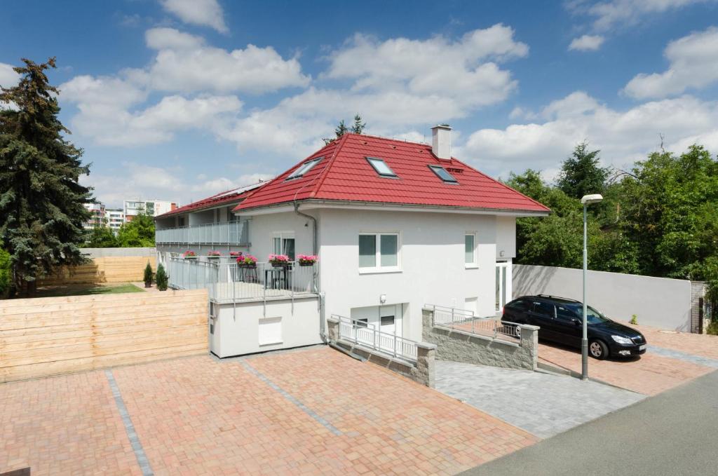 una casa blanca con techo rojo y un coche en Pension Zličín en Praga