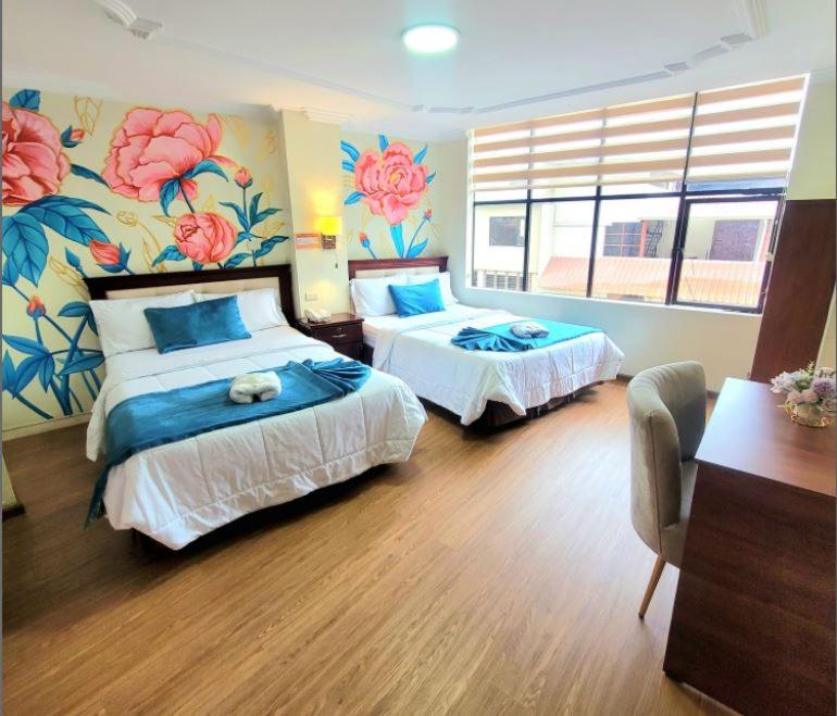 1 dormitorio con 2 camas con flores en la pared en Hotel Virgen del Cisne en Loja
