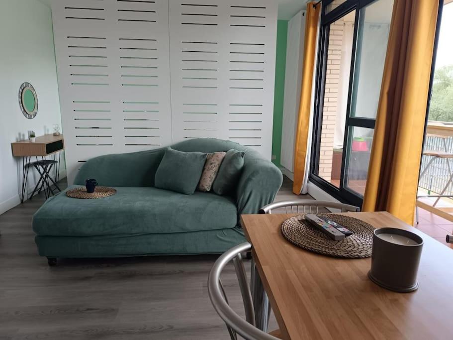 a living room with a green couch and a table at Appartement avec vue sur le lac in Lognes