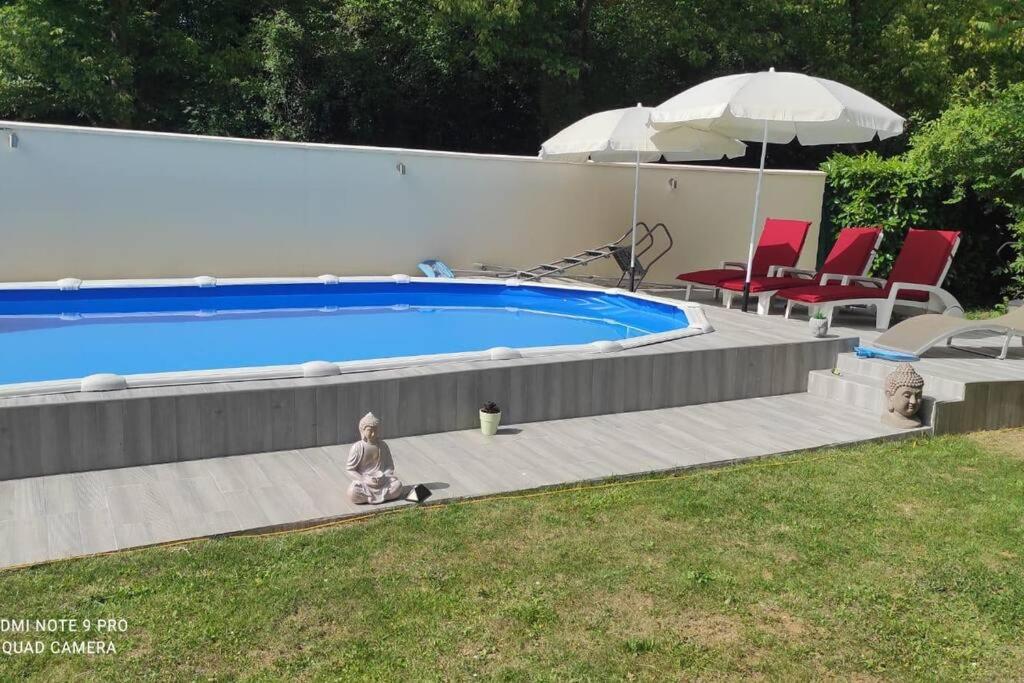 a woman is sitting next to a swimming pool at Villa d'exception avec Piscine in Villepinte