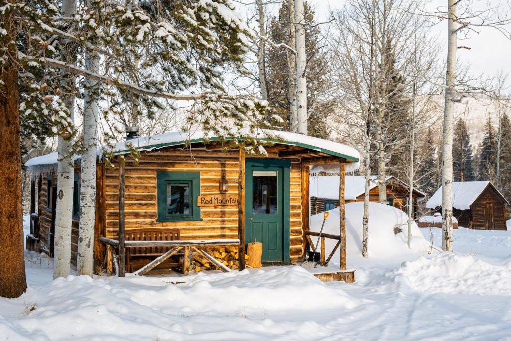 a wooden cabin with a green door in the snow at Beyul Retreat in Meredith