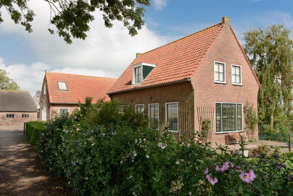 a brick house with a red roof at Buitenplaats Langewijk in Zuidoostbeemster