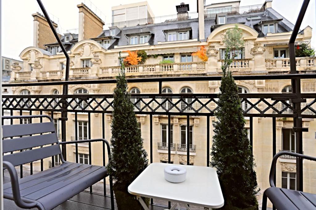 einen Tisch und eine Bank auf einem Balkon mit einem Gebäude in der Unterkunft Luxurious Flat Place Vendome in Paris