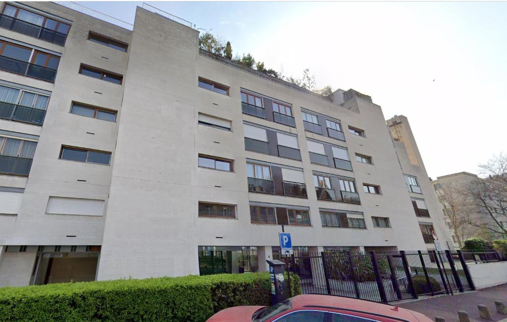 un grand bâtiment blanc avec une voiture garée devant. dans l'établissement Pret à usage & Commodat studette Résidence Schmit- 30 nuitées minimum - Salarié mobilité ou étudiant stagiaire, à Saint-Cloud