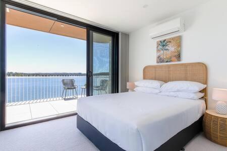 a bedroom with a bed and a balcony with a view at Lavish Coastal 2-Bed with Stunning Ocean Views in Batemans Bay