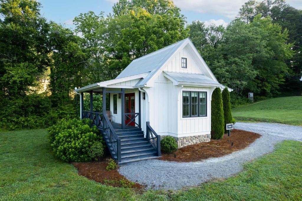 un pequeño cobertizo blanco con escaleras en un patio en Cottages @ Julep Farms, en Dillard