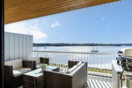 a patio with a view of the water and a balcony with furniture at Magnificent 1-Bed with BBQ and Views in Batemans Bay