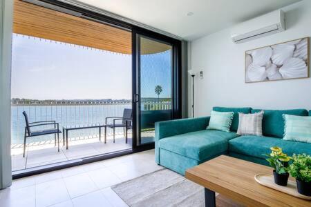 een woonkamer met een blauwe bank en een balkon bij Stunning 1-Bed Bayside Apartment with Superb Views in Batemans Bay