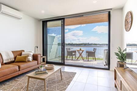 een woonkamer met een bank en uitzicht op het water bij Elegant Bay Side 1-Bed Apartment with Views in Batemans Bay