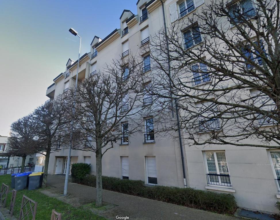 un bâtiment blanc avec un arbre devant lui dans l'établissement Pret à usage & Commodat Résidence Foch Saint-Louis - 30 nuitées minimum - Salarié mobilité ou étudiant stagiaire, à Poissy