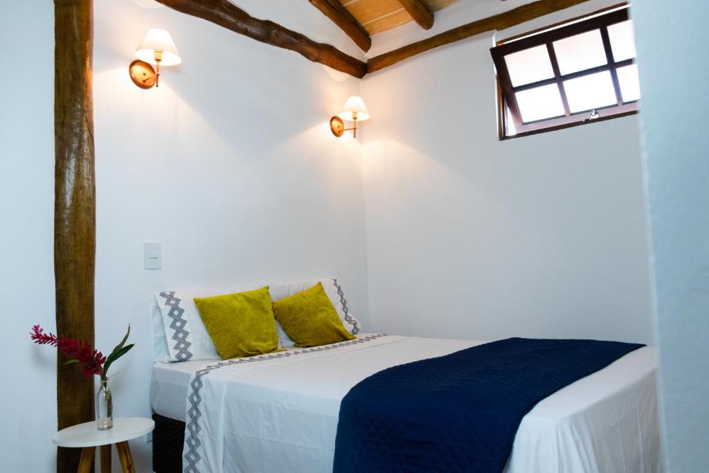 a bedroom with a bed with yellow and blue pillows at Suítes Margarida in Ubatuba