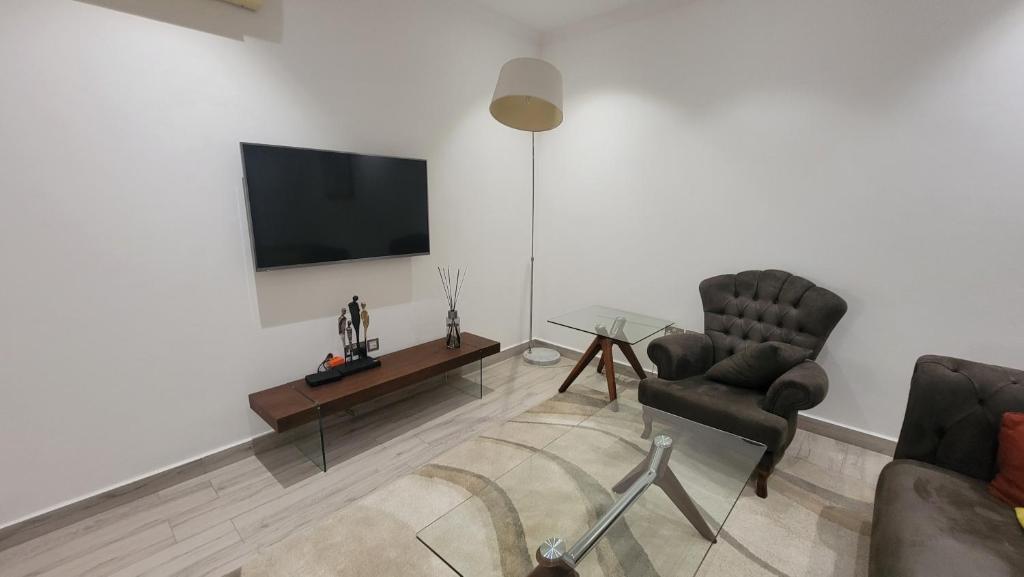 Acasia Luxury Home Cantonment في آكرا: غرفة معيشة مع كرسيين وتلفزيون