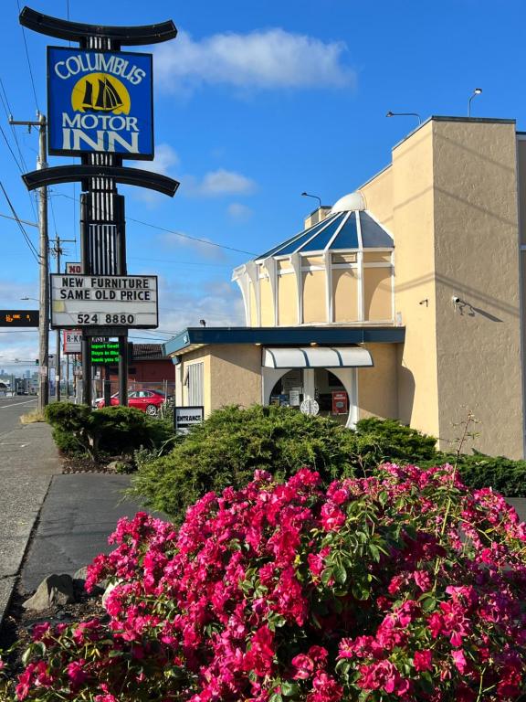 un cartel y flores delante de un motel en Columbus Motor Inn en Seattle