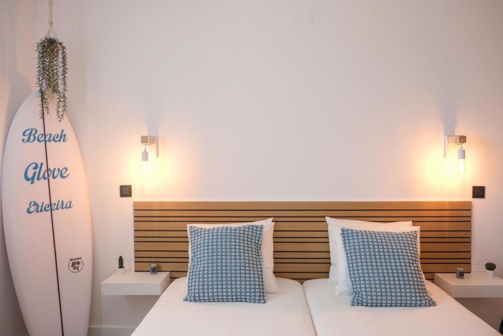 a bedroom with a surfboard and a bed with pillows at Beach Glove Ericeira II in Ericeira