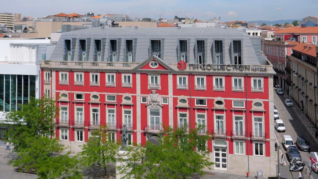 um edifício vermelho com um relógio em cima em NH Collection Porto Batalha em Porto