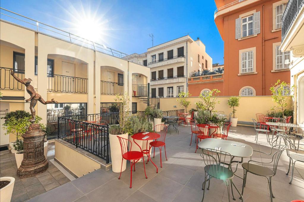 a patio with tables and chairs in a courtyard at Hôtel Apollinaire Nice in Nice