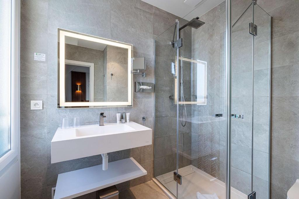a bathroom with a sink and a glass shower at Hôtel Apollinaire Nice in Nice
