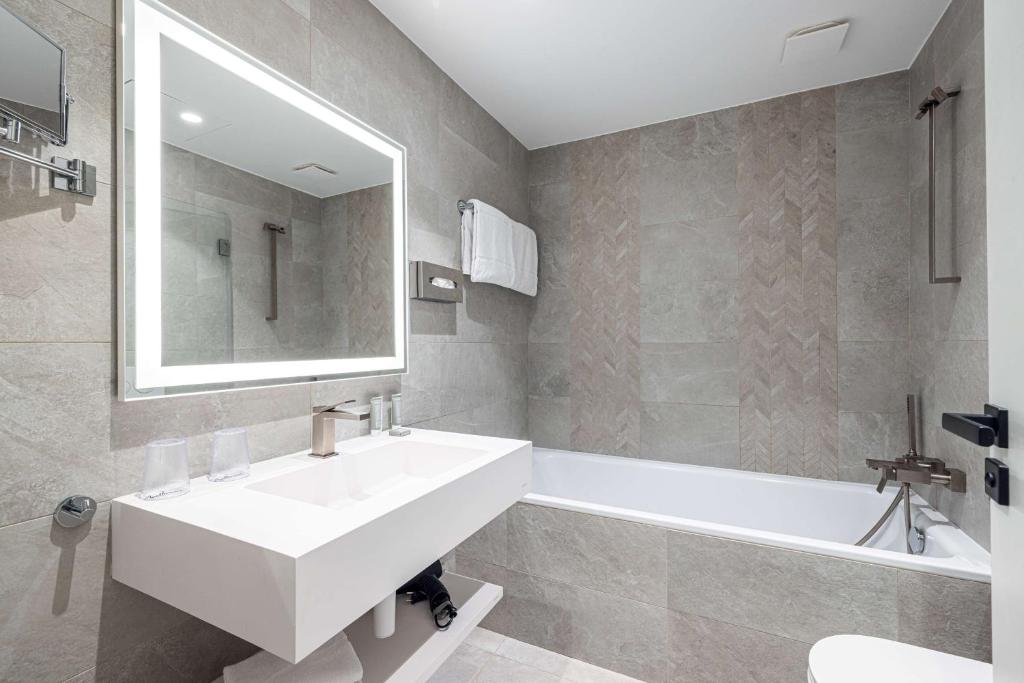 a bathroom with a sink and a tub and a mirror at Hôtel Apollinaire Nice in Nice