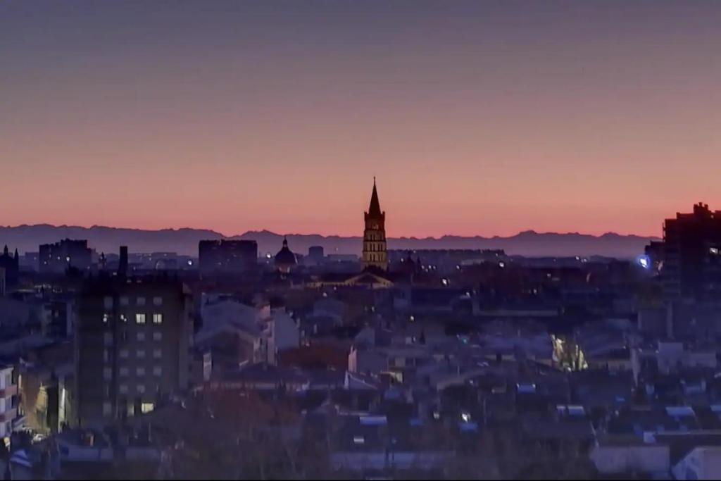 a city skyline at sunset with a clock tower at Chambre & table d'hôte à 5 min de la gare Matabiau in Toulouse