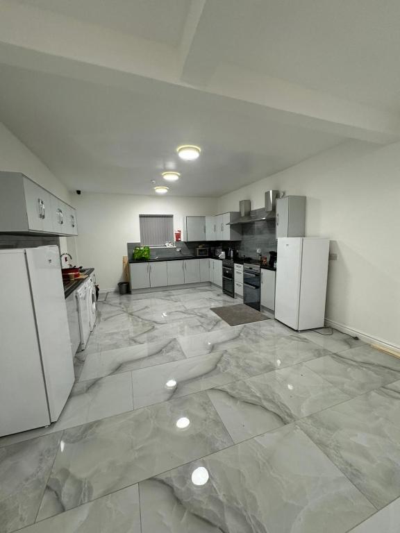 a large kitchen with white appliances on a marble floor at Vic Vic property in Oldham