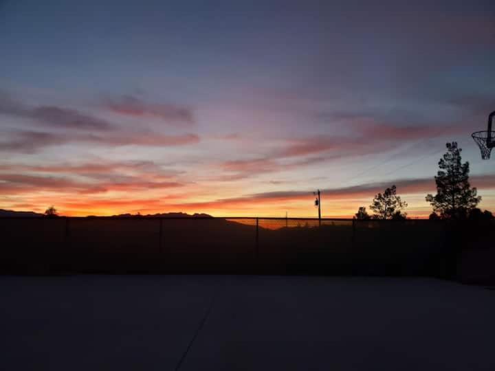 a sunset over a field with a fence and trees at Sun Tiny House D Pahrump in Pahrump