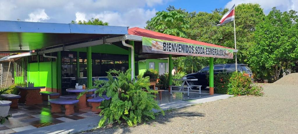 a green building with tables and chairs and a flag at Esmeralda in Puerto Jiménez