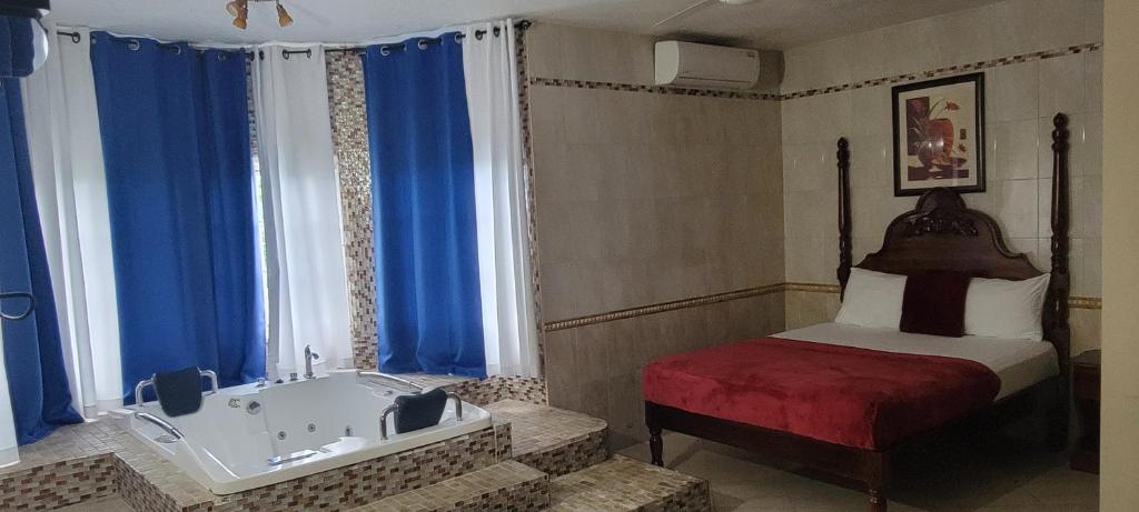 een slaapkamer met een bad en een bed met blauwe gordijnen bij Wizzy Apartment White River in Ocho Rios