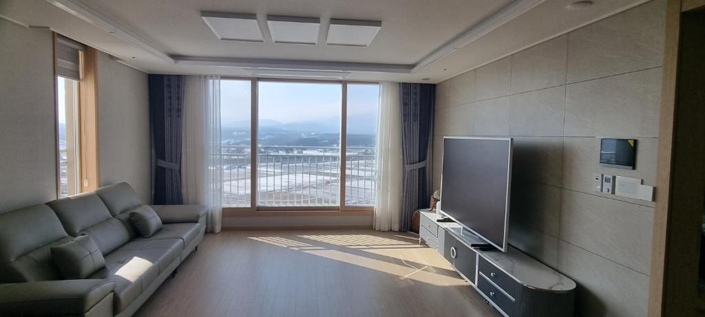 Gangneung Sacheon beach Happy House في جانجنيونج: غرفة معيشة مع أريكة وتلفزيون بشاشة مسطحة