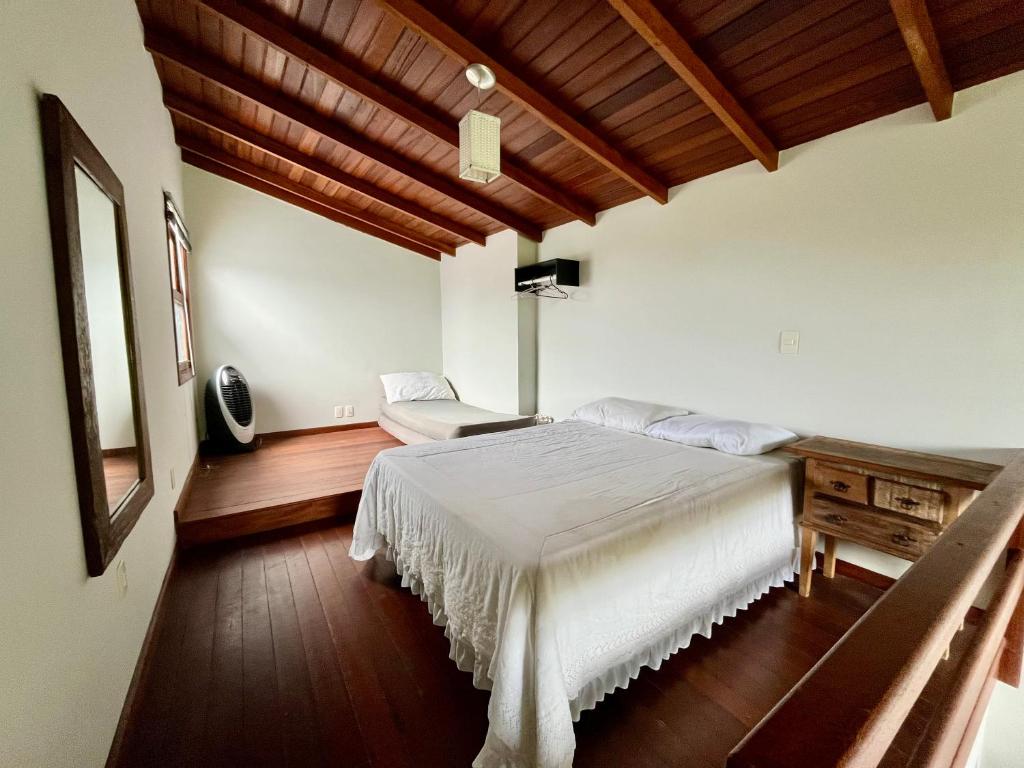 1 dormitorio con 1 cama blanca y 1 silla en Jardim do Sol Residence, en Palhoça