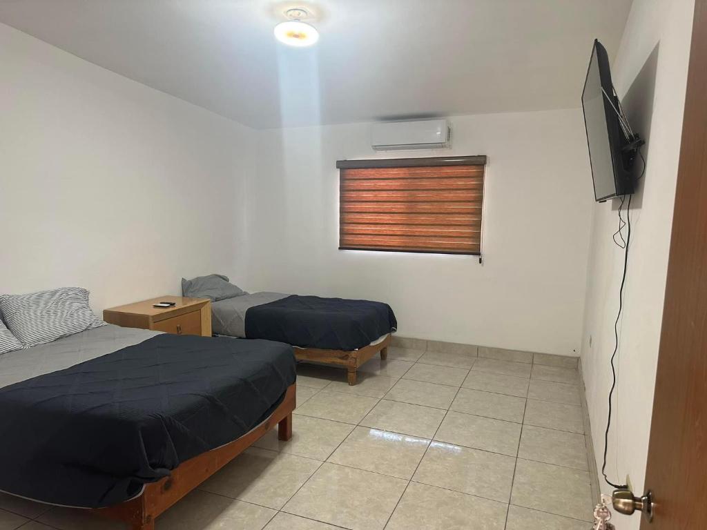 een kamer met 2 bedden en een televisie. bij Habitaciones ENMA in Ciudad Juárez