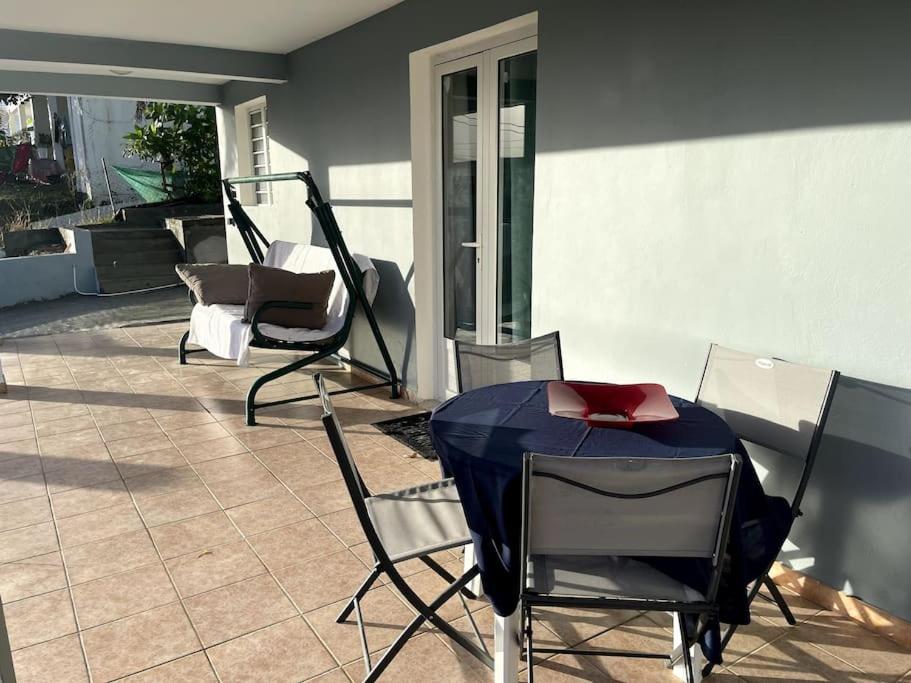 d'une terrasse avec des chaises et une table avec un oreiller rouge. dans l'établissement Appartement tout équipé proche des plages, à Sainte-Luce