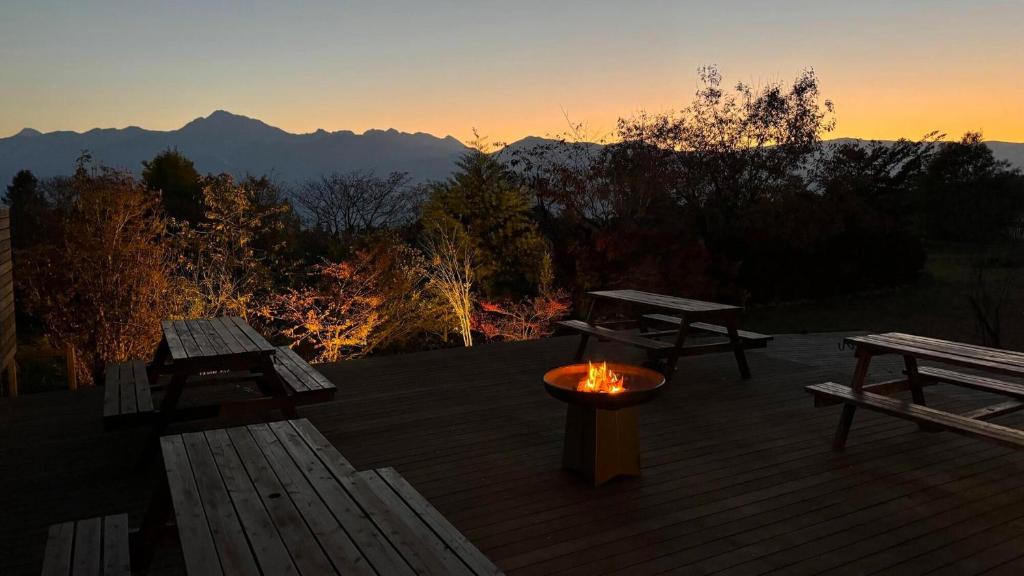 eine Terrasse mit zwei Picknicktischen und einer Feuerstelle in der Unterkunft Place yatsugatake Lodge&cottage in Hokuto