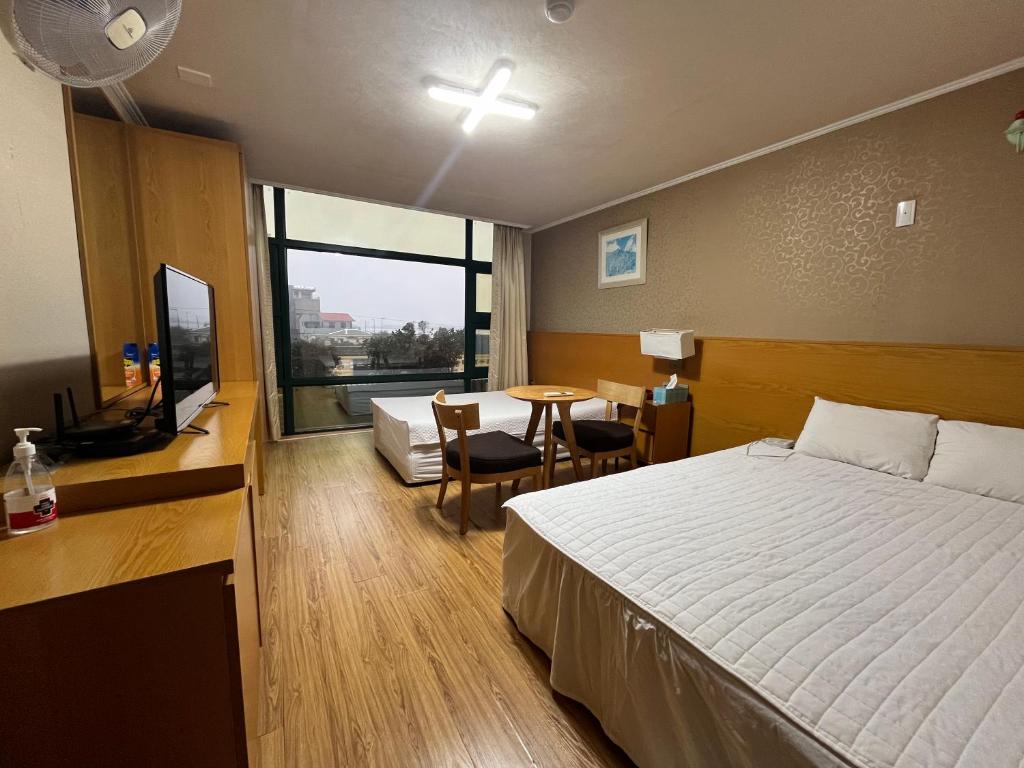 een slaapkamer met een bed, een bureau en een tafel bij Seongsan Motel in Seogwipo