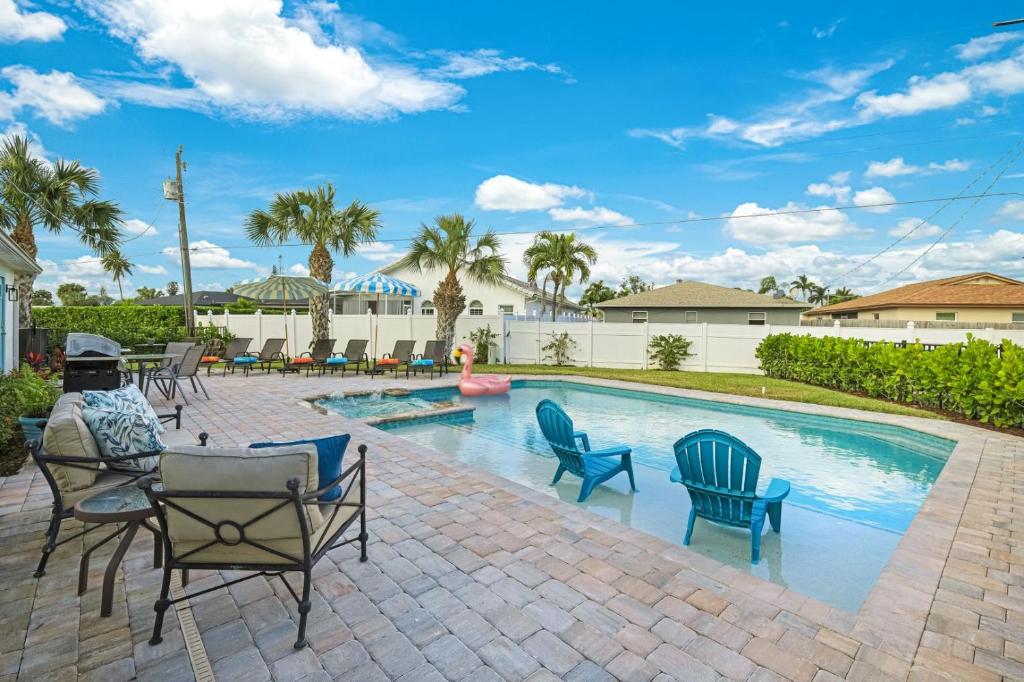 a swimming pool with blue chairs and a man sitting next to it at New Listing! Beach Walk Newly Renovated - Walk To Vanderbilt Beach! in Naples