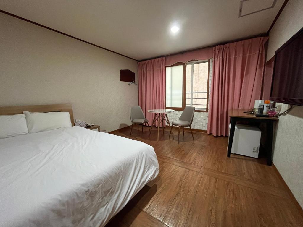 1 dormitorio con 1 cama, mesa y sillas en Oreum Motel en Jeju