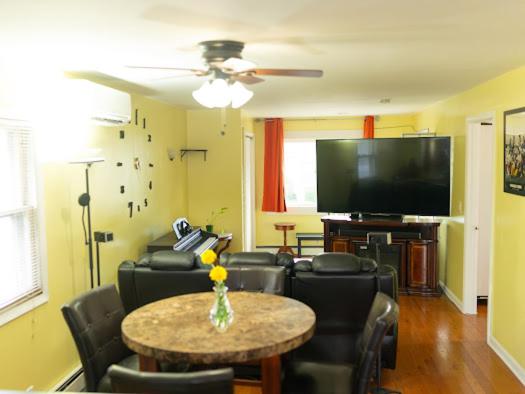 sala de estar con mesa y TV de pantalla plana en Fairmount Place, en Fair Lawn