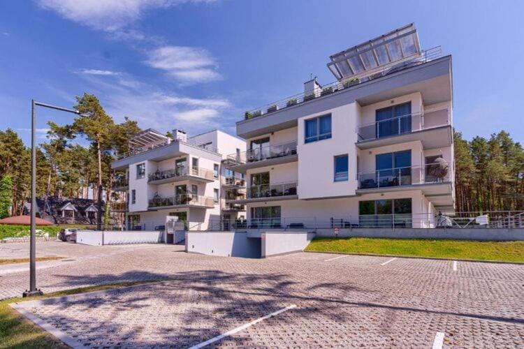 a large white apartment building with a parking lot at Comfortable apartment near the sea, Pobierowo in Pobierowo